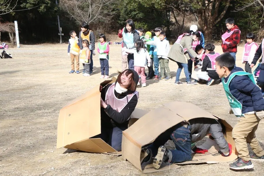 広場で段ボール遊びをする子どもとリーダー
