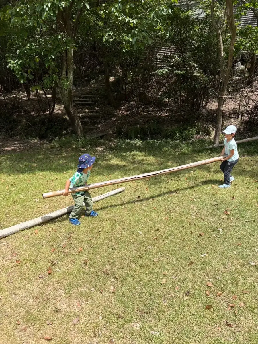 竹を持って芝生を走る子どもたち